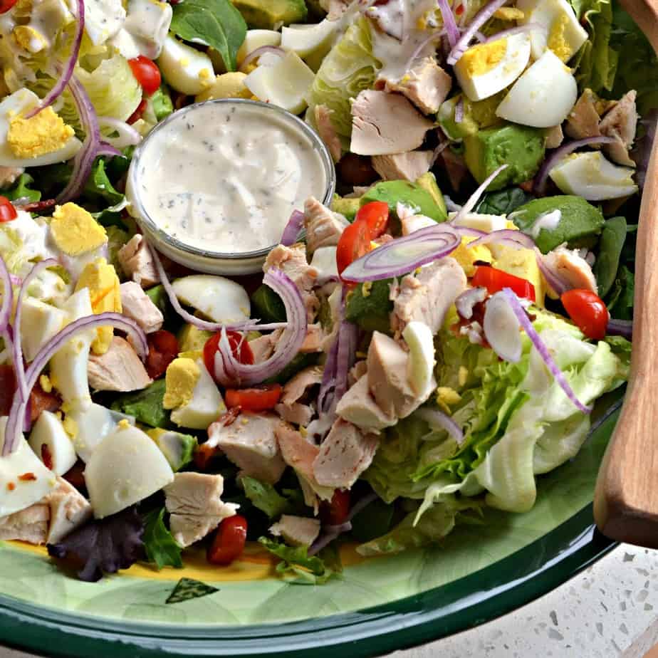 This classic Wedge Salad combines bacon crumbles, tomatoes, red onions, hard-boiled eggs, avocado, and cooked rotisserie chicken all under a blanket of creamy blue cheese dressing or ranch dressing.