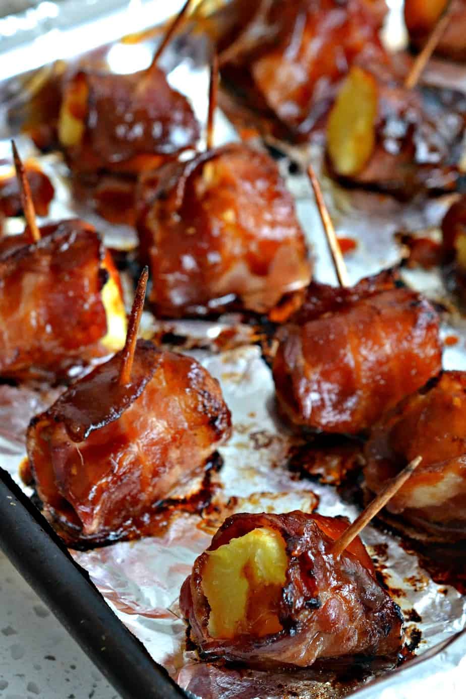 Fresh pineapple chunks are wrapped in crisp bacon and basted with a slightly spicy, tangy sweet sauce.  They are perfect for game day, cocktail night, and baby and bridal showers.  