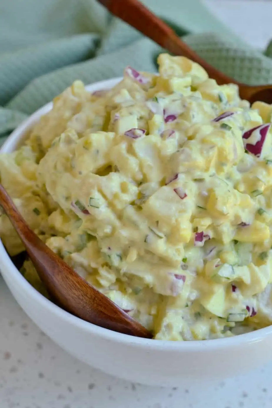 A close up of homemade potato salad with dill pickles. 