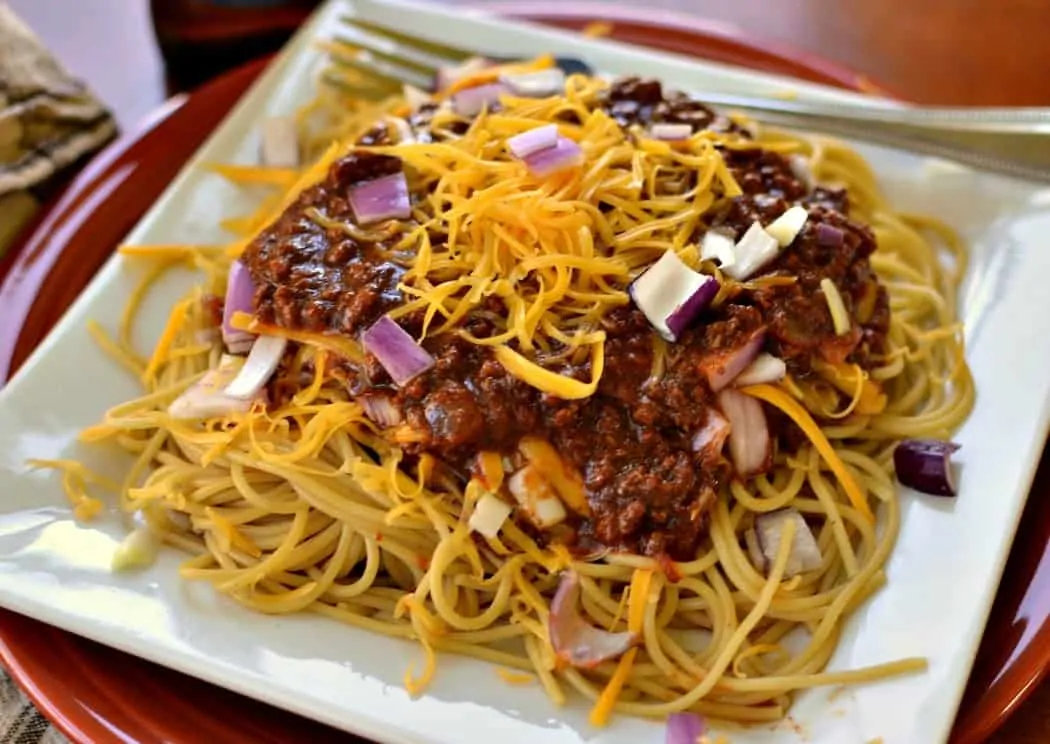 Cincinnati Chili is traditionally served over spaghetti noodles with shredded cheddar and onions.