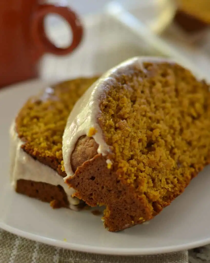 Two slices of glazed pumpkin bread on a plate. 