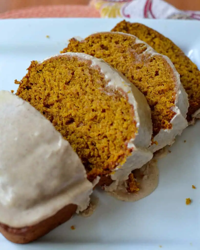 Slices of glazed pumpkin bread on a serving plate. 