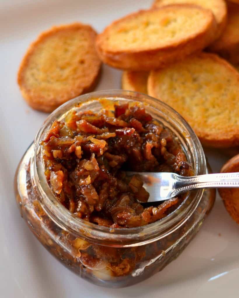 An overhead view of bacon jam with crostinins on a plate. 