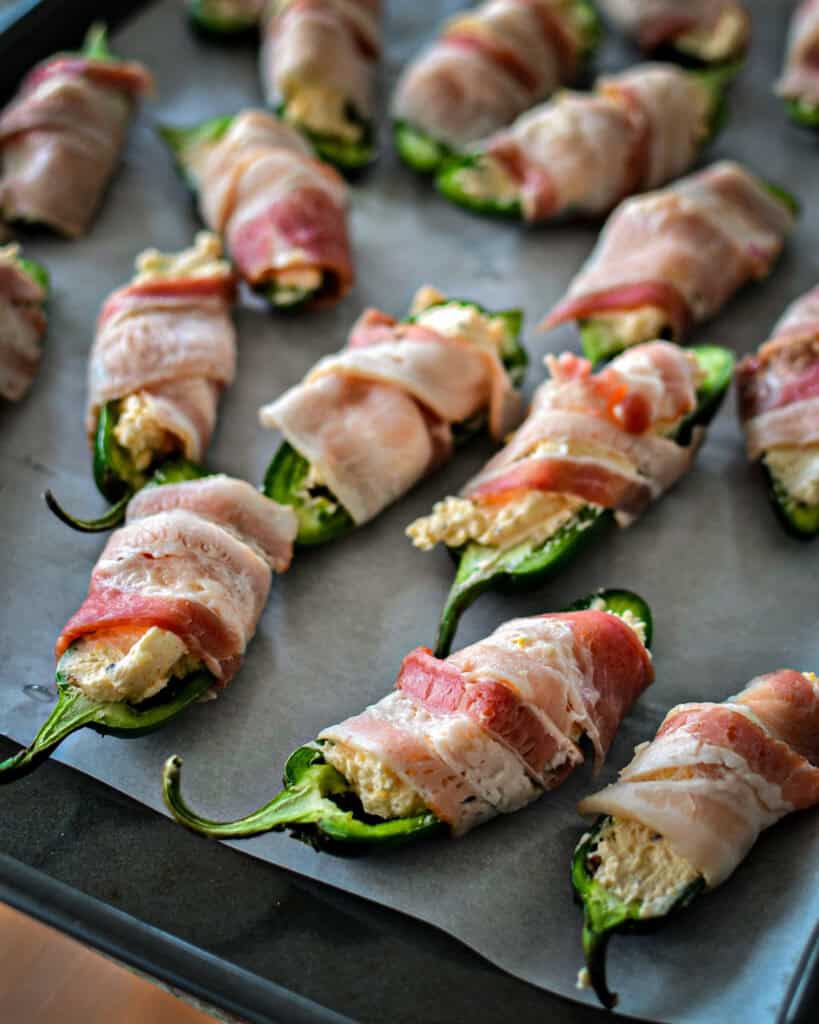 Wrap the stuffed pepper with one-half slice of bacon. Place the seam side down on a baking sheet.