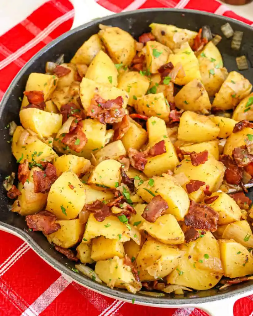 A close up view of German Potato salad with crisp bacon, tender onions, and chopped fresh parsley.
