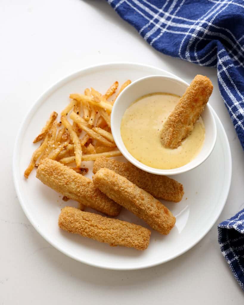 Honey Mustard Sauce for Chicken A single serving plate with fish sticks, fries, and mustard sauce.