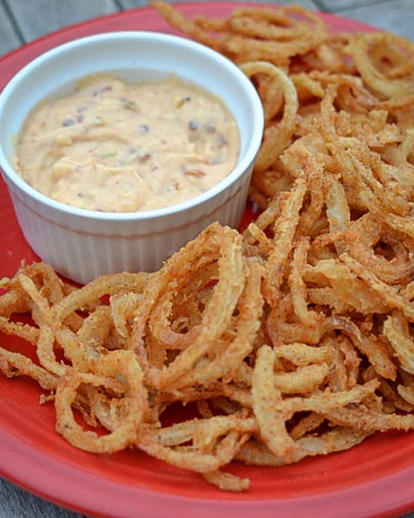 Onion straws on a plate with comeback dipping sauce. 