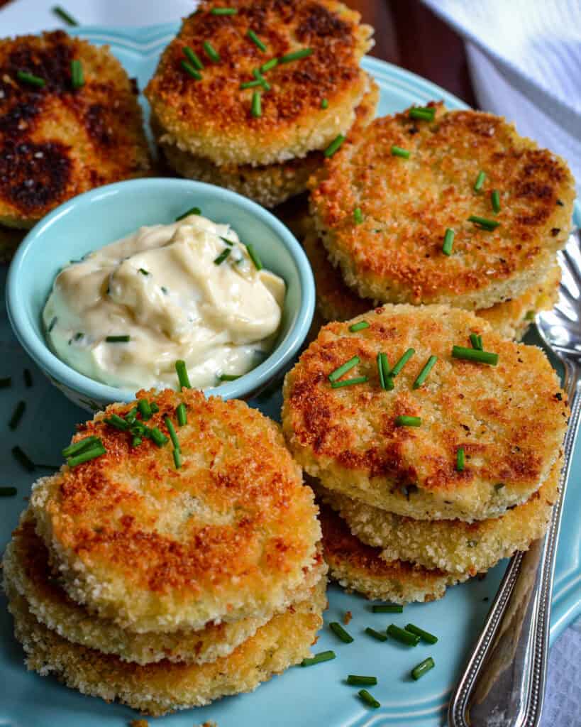 Stacked Potato Croquettes with garlic aioli dip in the middle and chives on top.