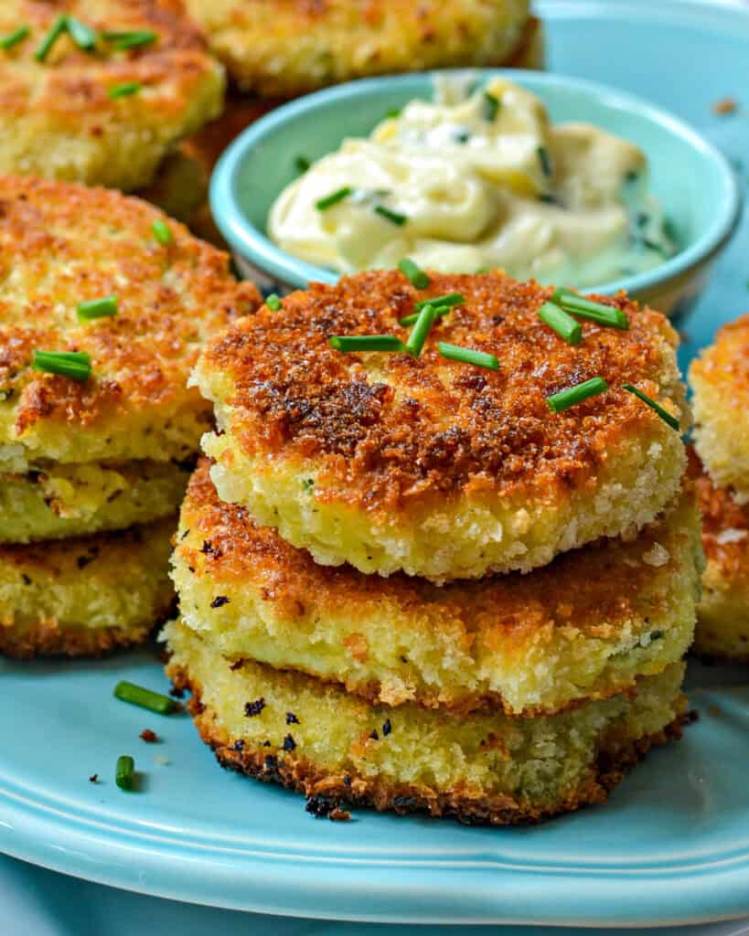 Crispy Potato Croquettes plated with garlic aioli and chives on top.