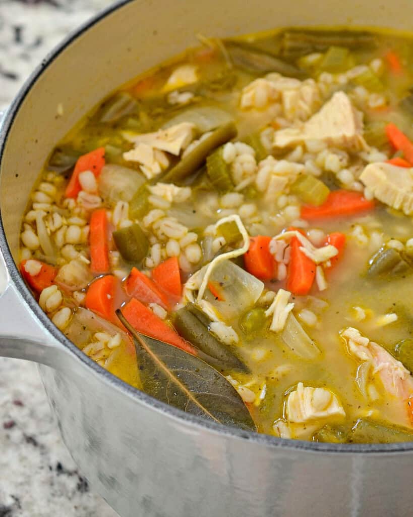 Chicken Barley Soup A close up shot of a Dutch oven full of chicken barley soup.