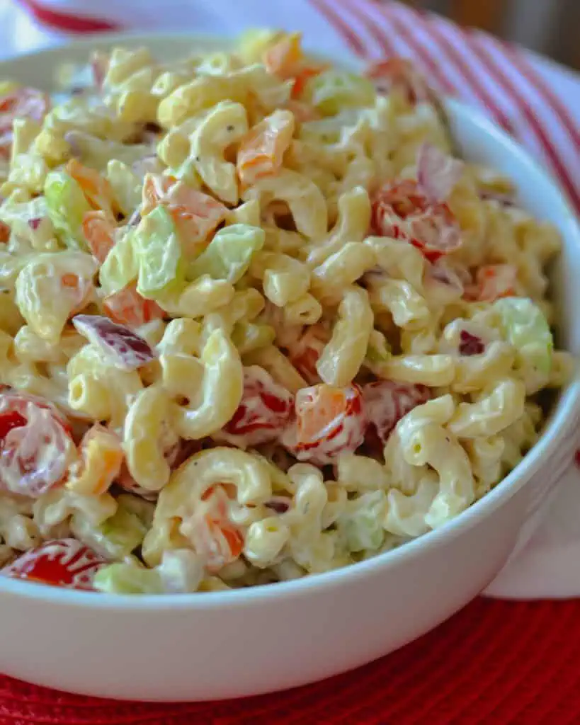Best Macaroni Salad Recipe A bowl full of cold mayonnaise macaroni salad with bell peppers, tomatoes, onions, and celery.