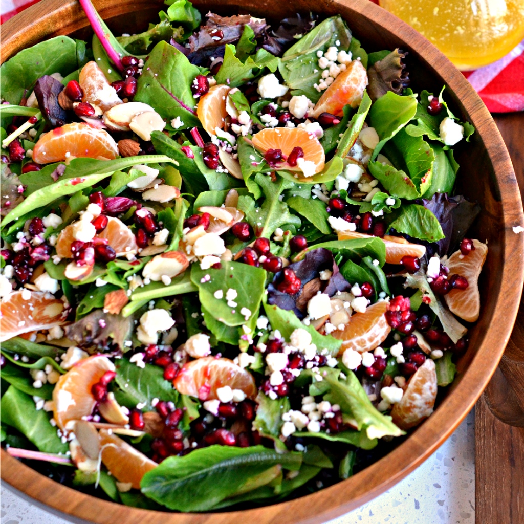 Christmas Green Salad is topped with fresh mandarins, feta cheese, almonds, and pomegranate seeds.