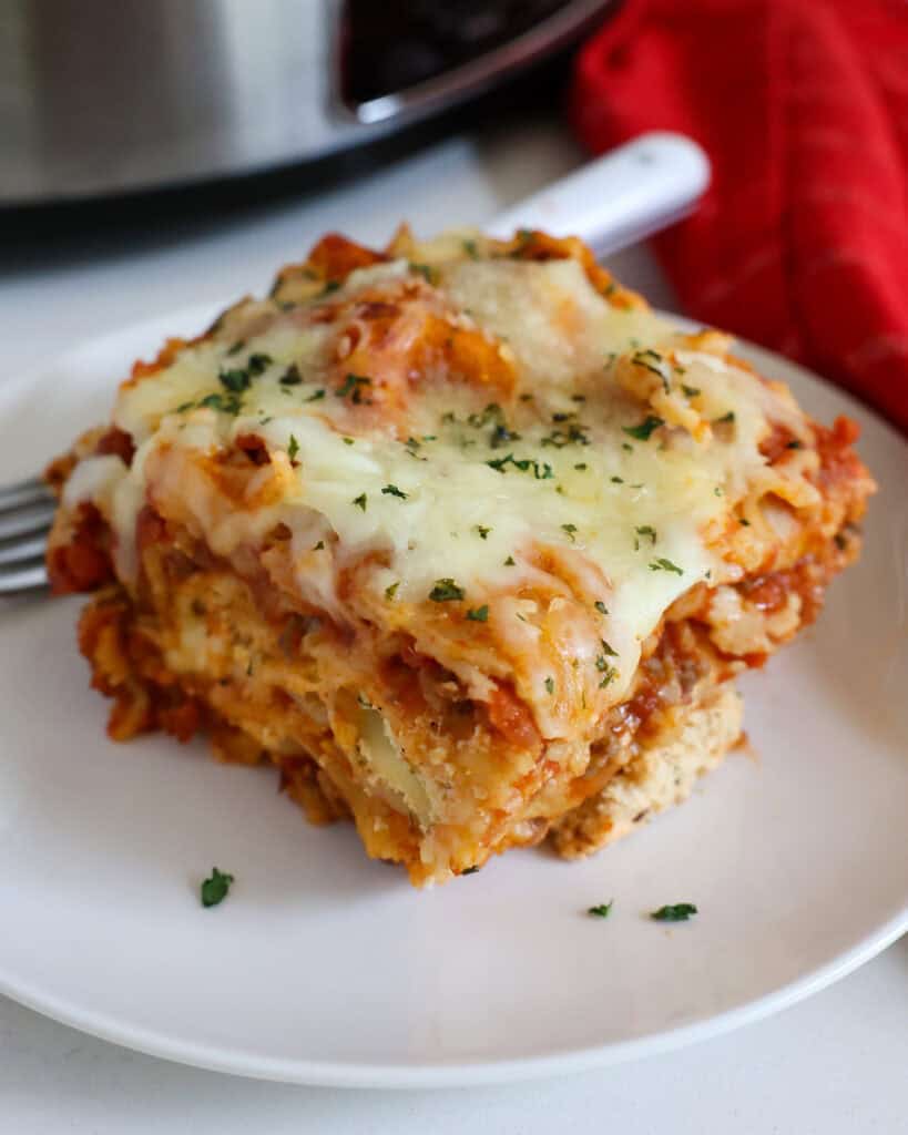 A piece of crock pot lasagna on a single serving plate with a fork
