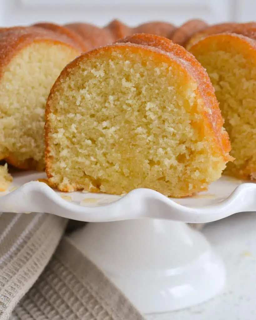 A close up view of a piece of Kentucky butter cake on a cake stand with the rest of the cake. 