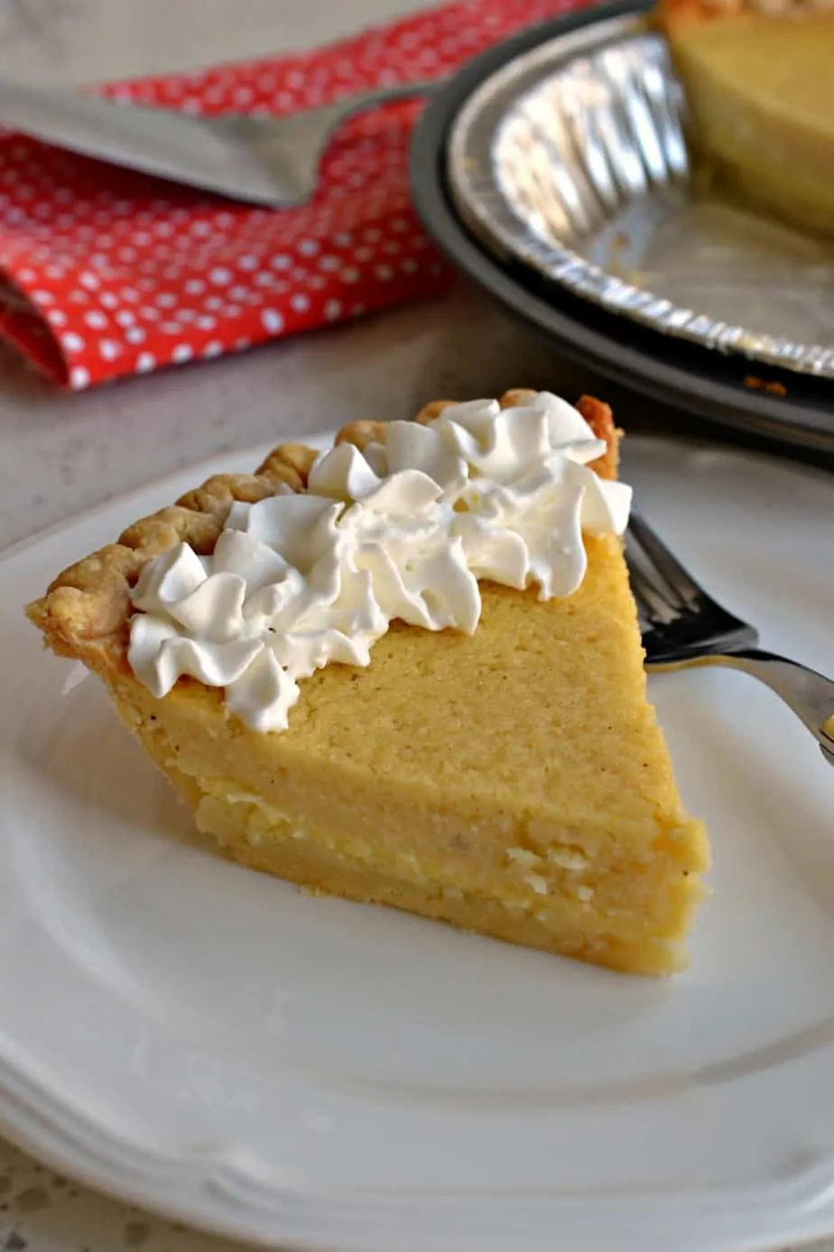 A delicious slice of buttermilk pie topped with fresh whipped cream is the perfect dessert