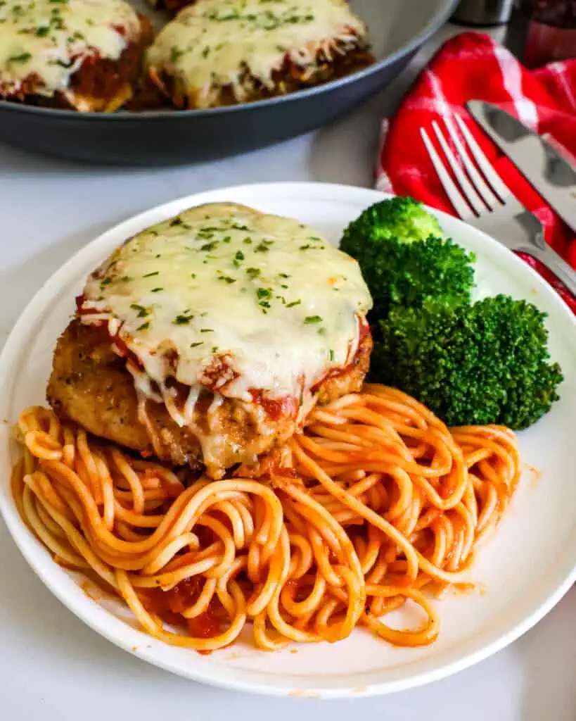 a close up view of chicken parmesan over spaghetti. 