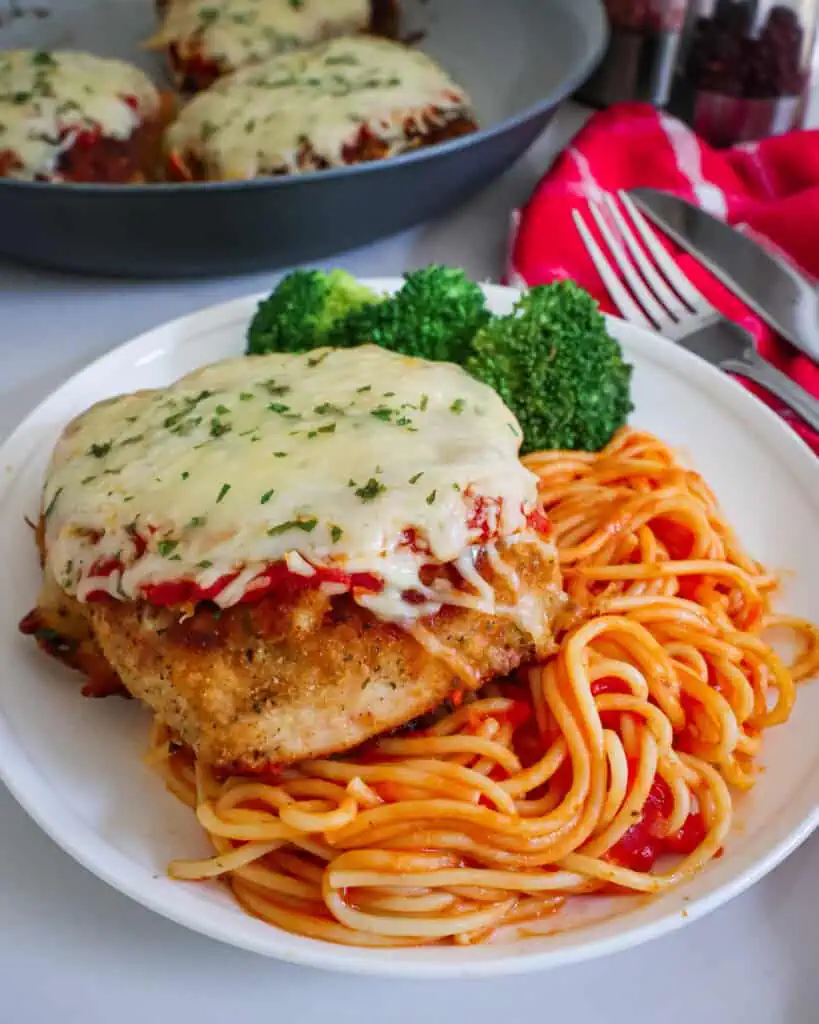 A single serving plate with chicken parmesan over spaghetti with broccoli on the side.