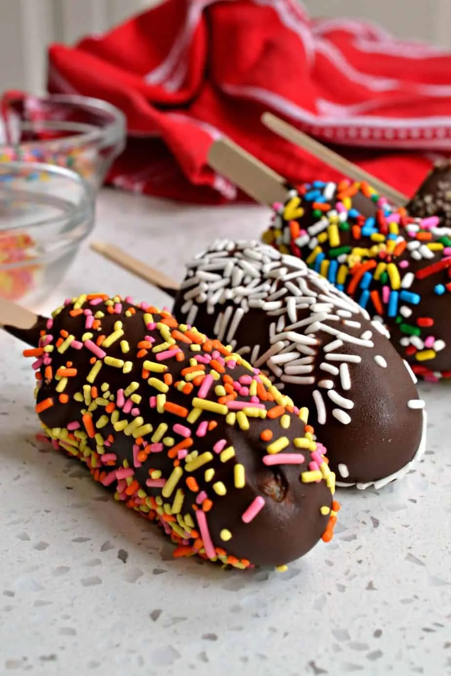 These delectable Frozen Chocolate Covered Bananas, also know as Banana Pops are dipped in rich chocolate and sprinkled with nuts, oats, graham crackers and sprinkles.  