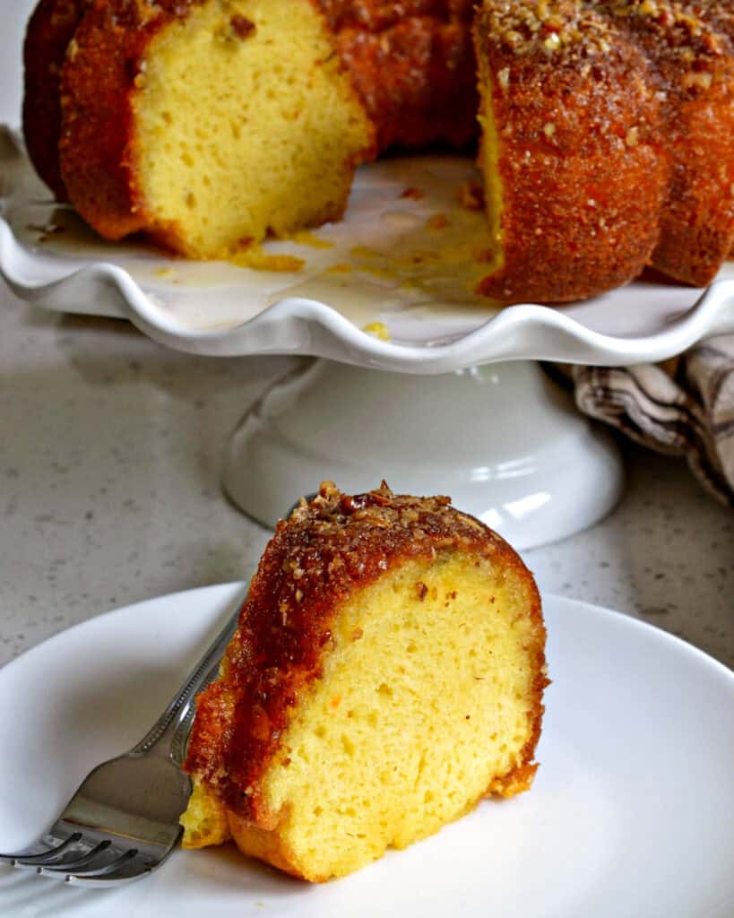 A slice of Rum Cake standing up on a plate with a fork.
