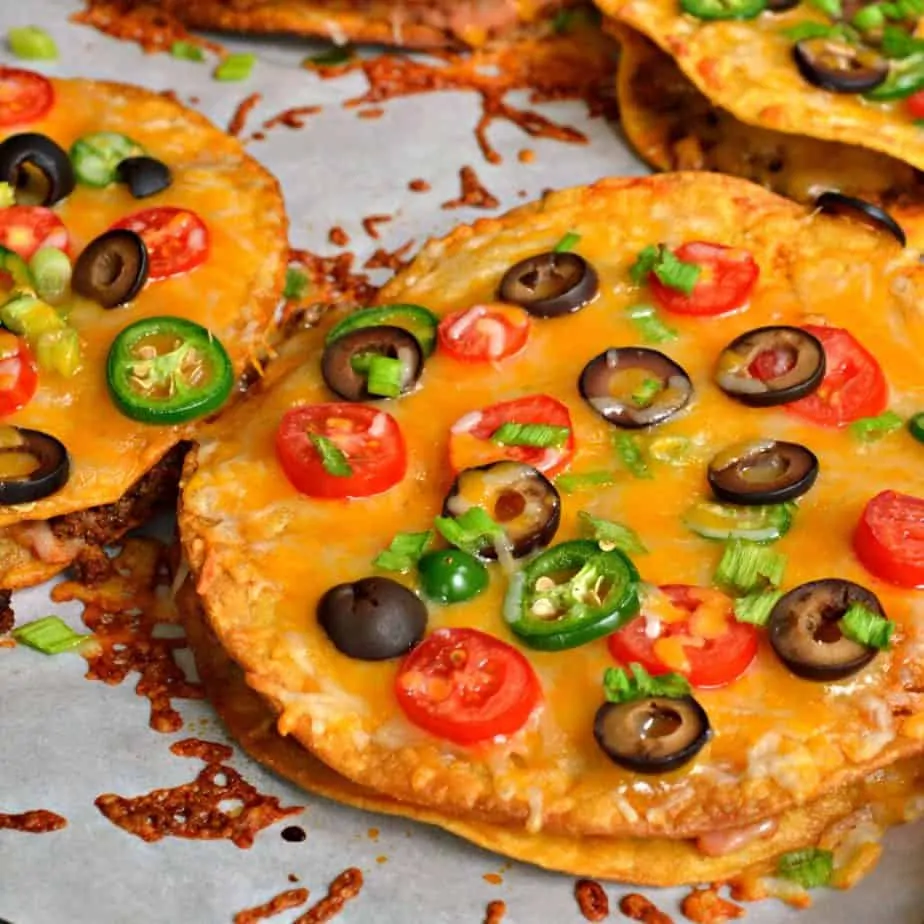 Mexican Pizzas stuffed with refried beans and taco seasoned ground beef then topped with oodles of cheese and tomatoes.