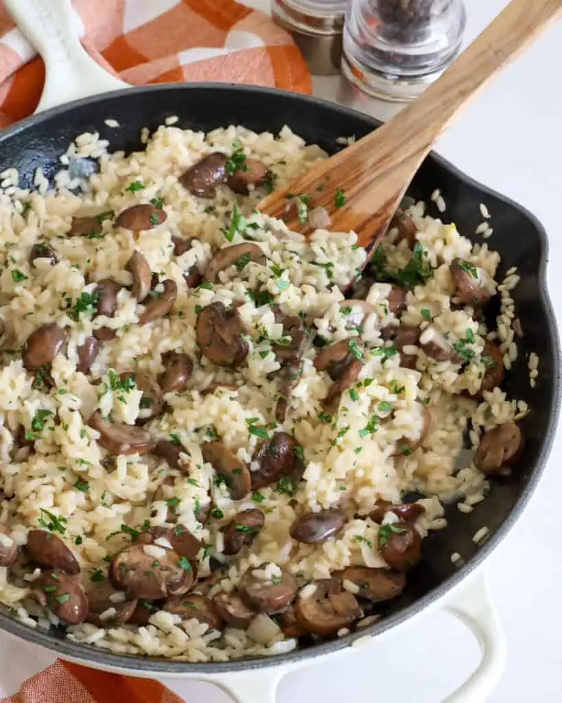 A large skillet full of mushroom risotto sprinkled with chopped fresh Italian parsley. 