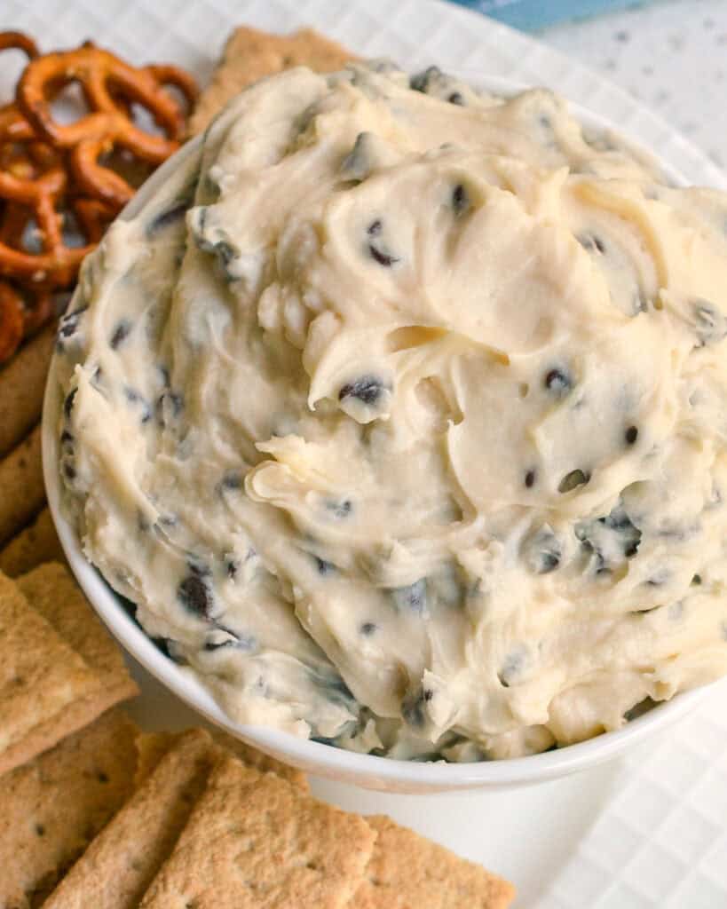 An overhead view of a cookie dough dip with graham crakers and pretzels on the side.