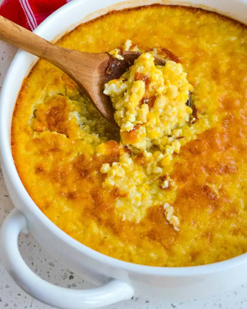 An overhead view of a large round casserole dish full of fresh baked corn pudding.