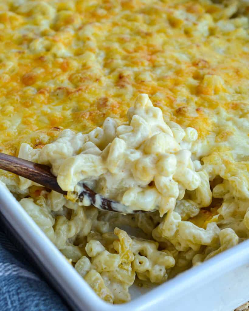A casserole dish and a wooden spoon full of baked macaroni and cheese.
