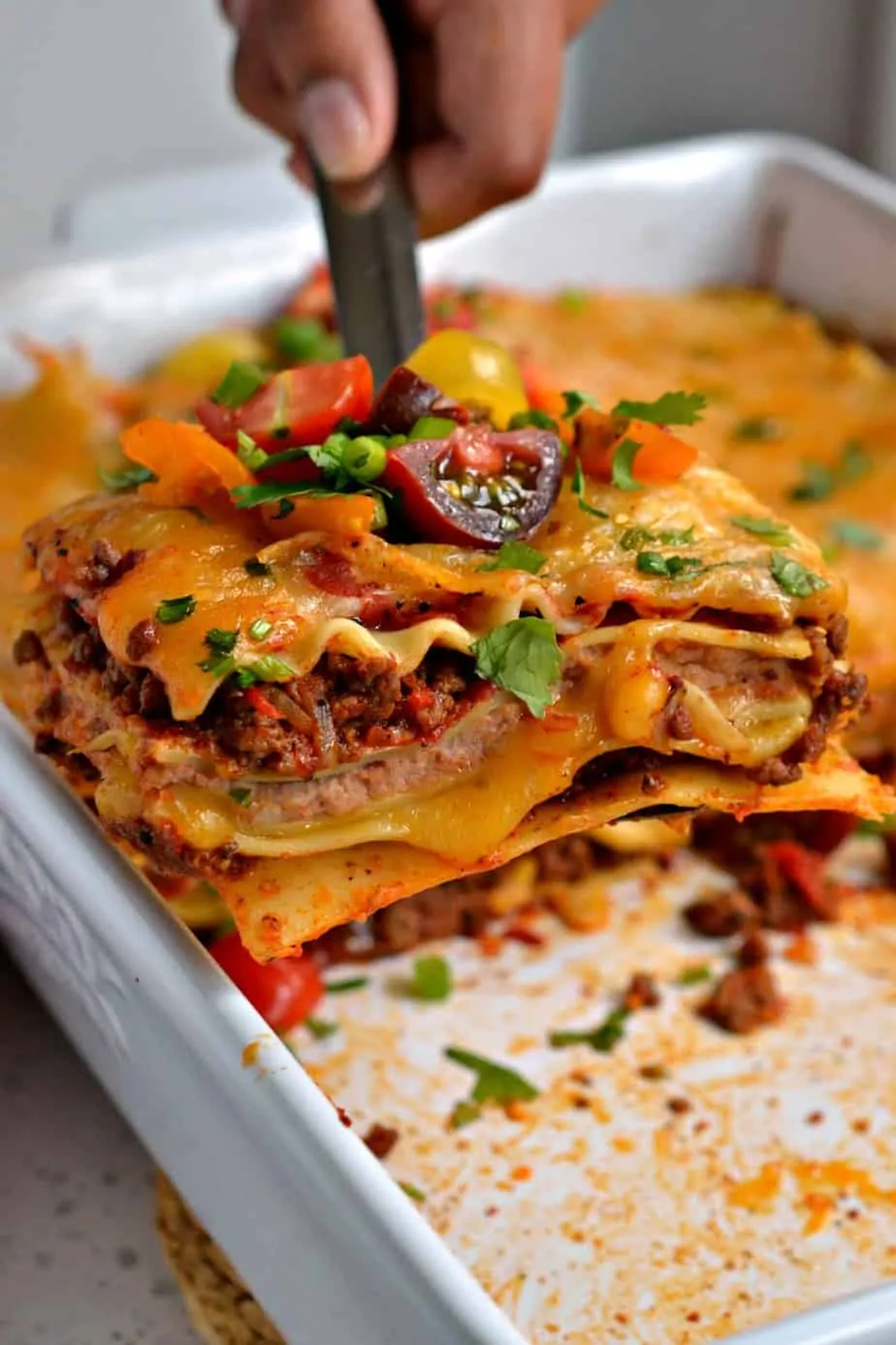 Mexican Lasagna is a hearty meal with an abundance of flavors from taco seasoned ground beef, onions, and refried beans. 