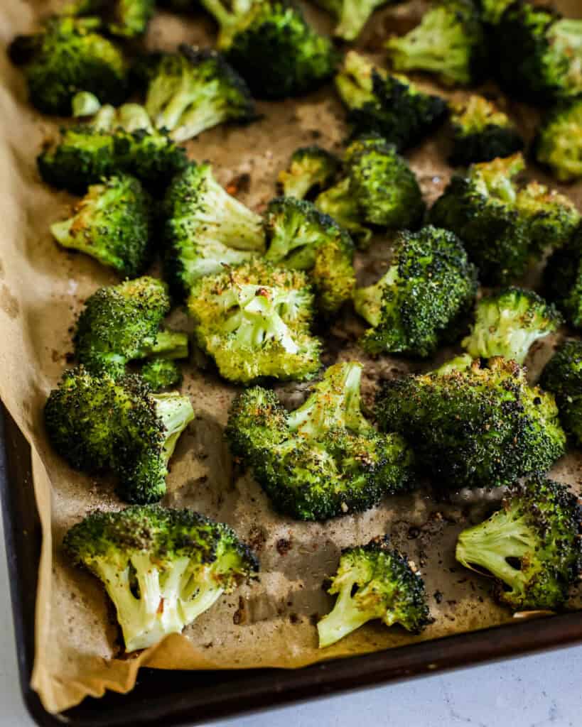 Roasted broccoli on a baking sheet covered with parchment paper. 