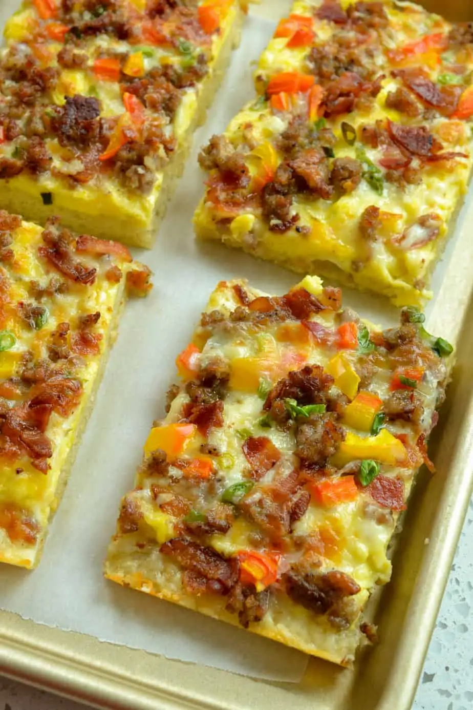 Breakfast pizza on a parchment paper covered baking sheet. 