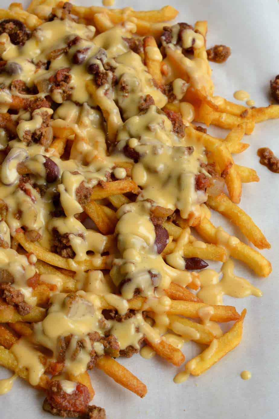 Scrumptious Chili Cheese Fries made with a hearty thick beef chili and topped with a lusciously creamy cheddar cheese sauce