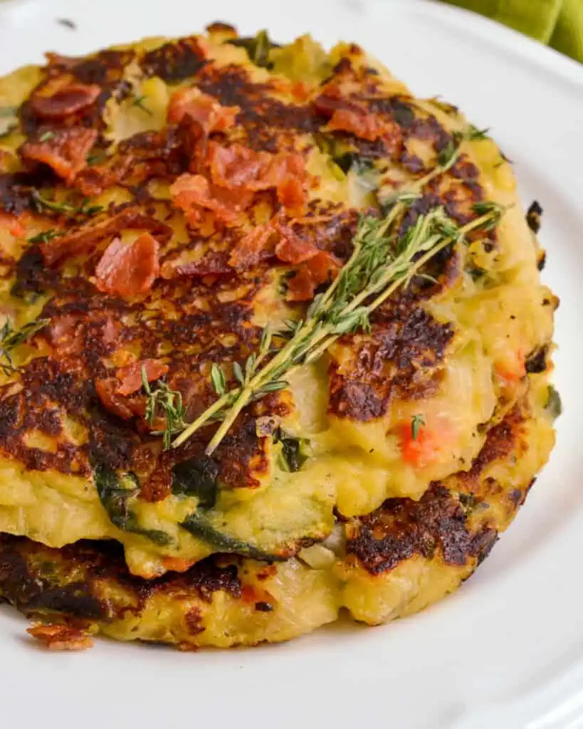 Two bubble and squeak patties stacked on a plate. 