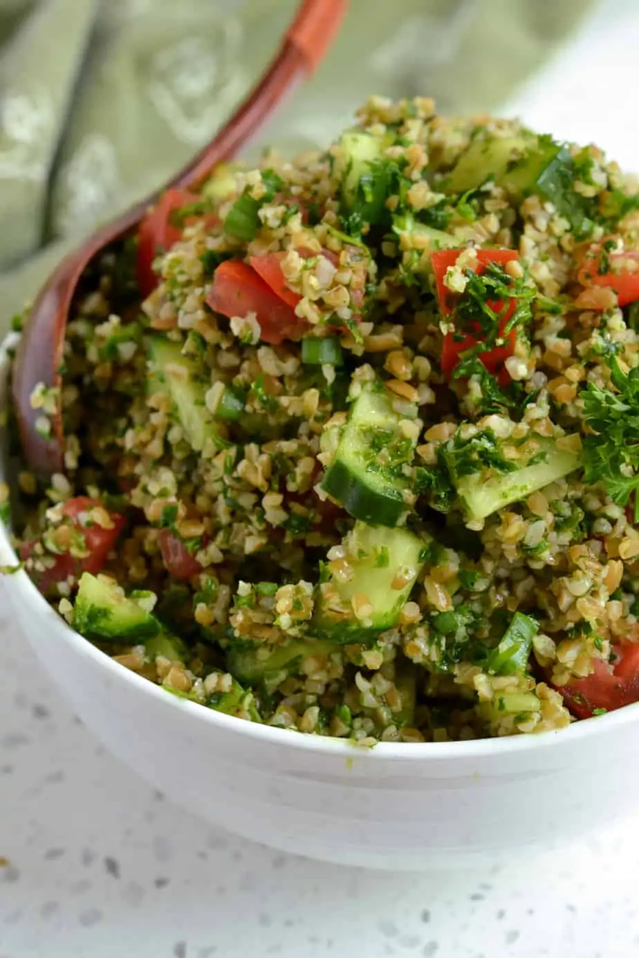 A salad with bulgur wheat, cucumbers, tomatoes, scallions, parsley and mint all drizzled with lemon and olive oil. 