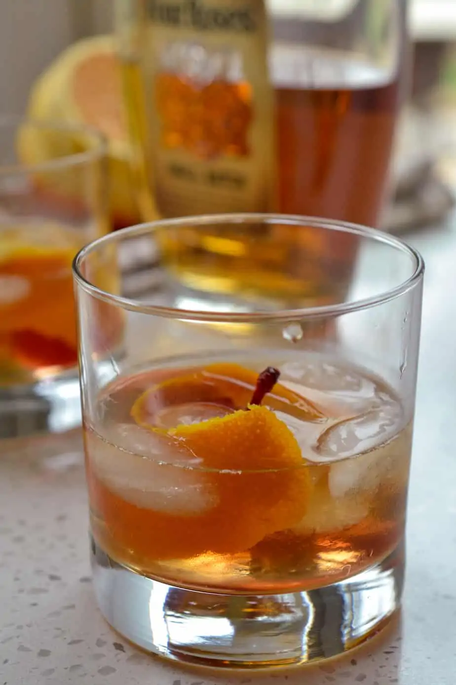 Old fashioned bourbon whiskey cocktail with orange twist and maraschino cherry. 