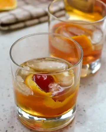 Old fashioned cocktail with orange twist and maraschino cherry