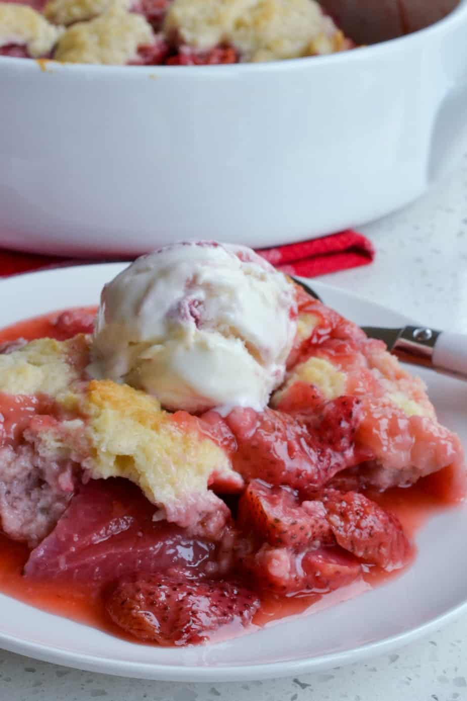A plate full of strawberry cobbler with vanilla ice cream. 