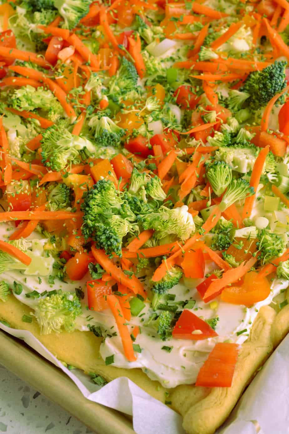 Crescent roll pizza topped with ranch cream cheese and vegetables. 