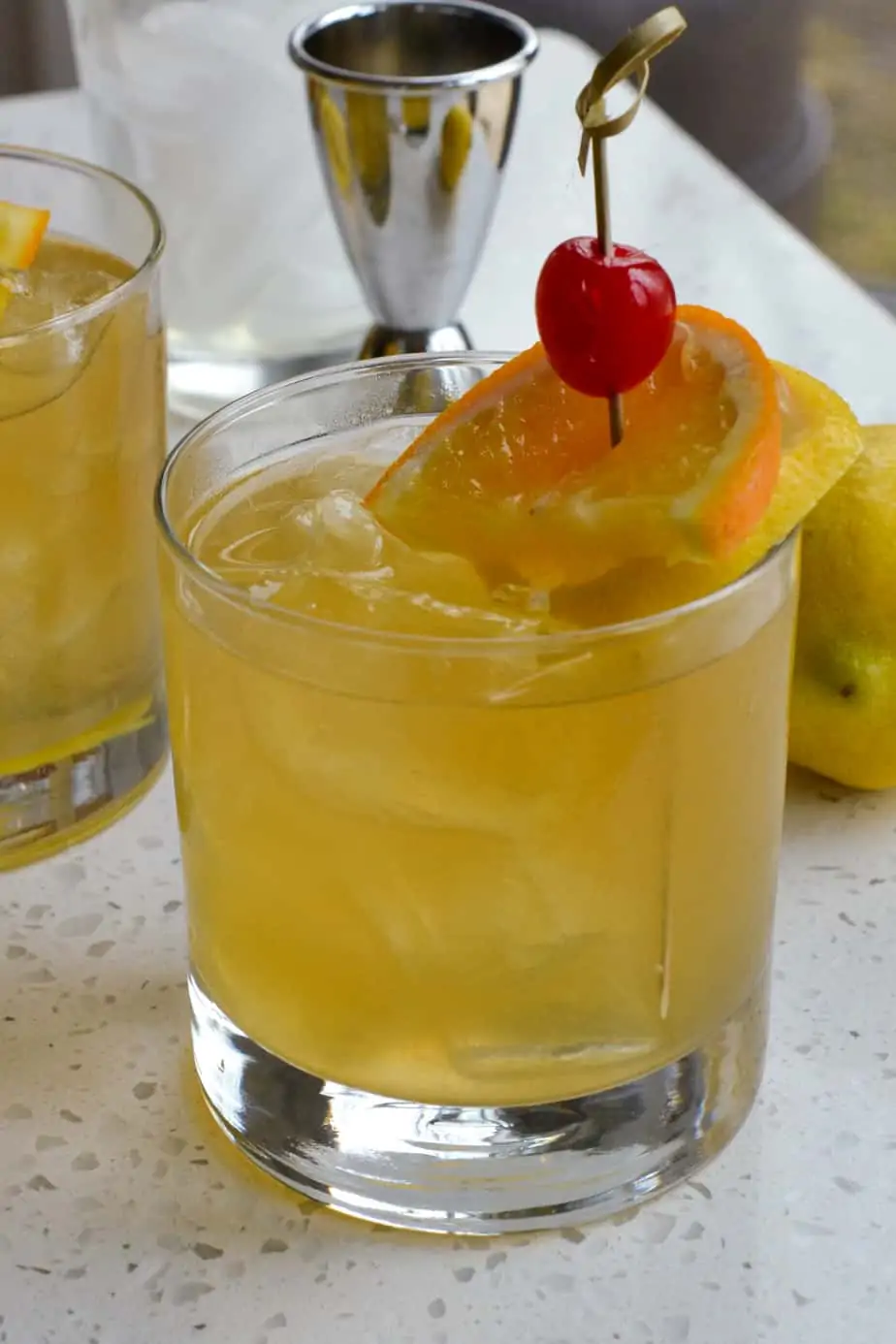 Whiskey sour cocktail garnished with an orange slice, lemon slice, and cherry. 
