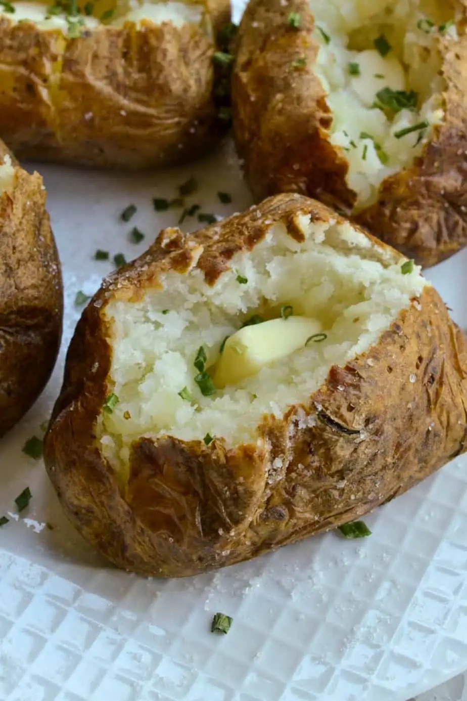 Air fryer baked potatoes topped with butter and chives
