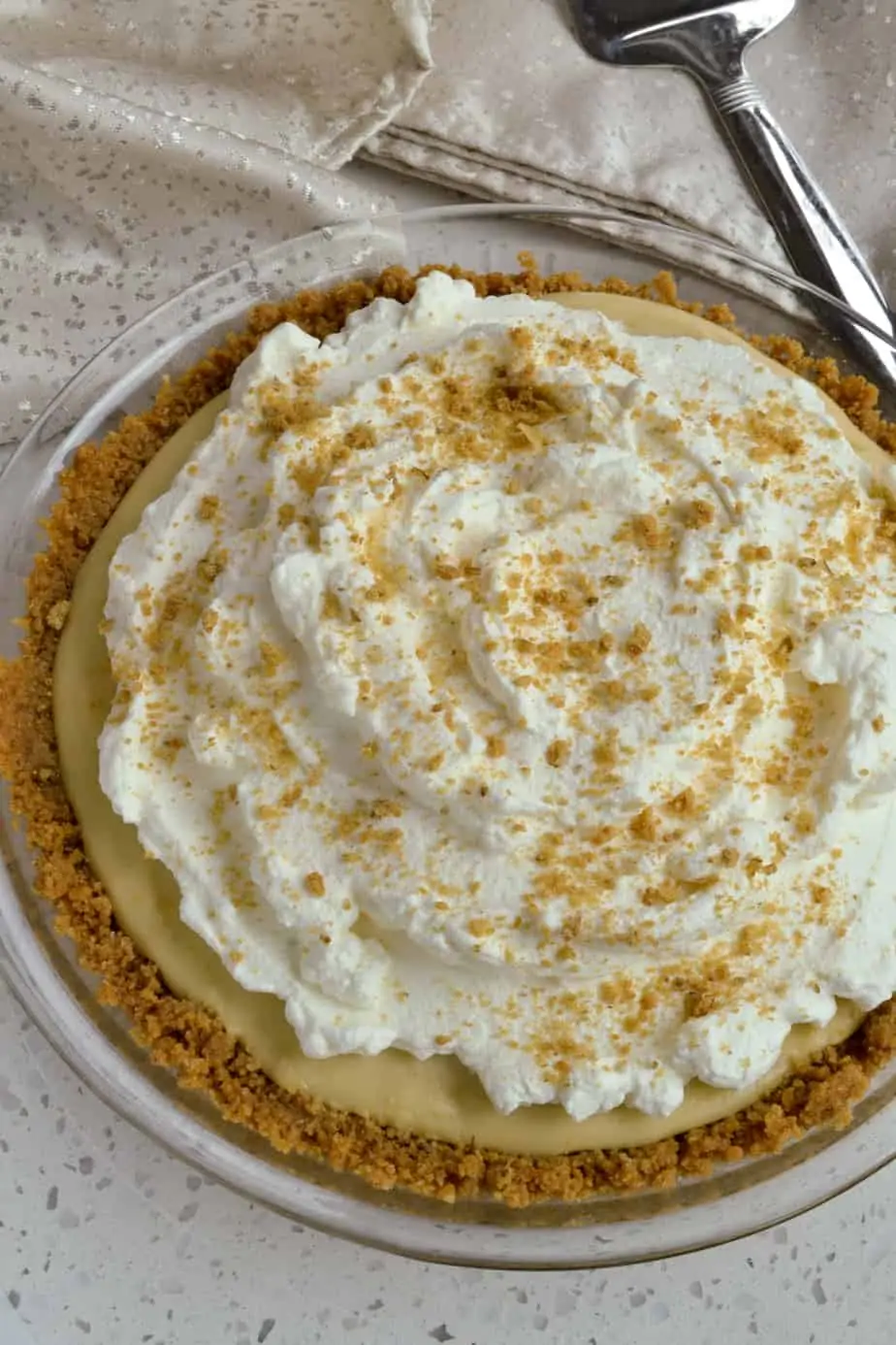 A whole butterscotch pie topped with whipped cream. 