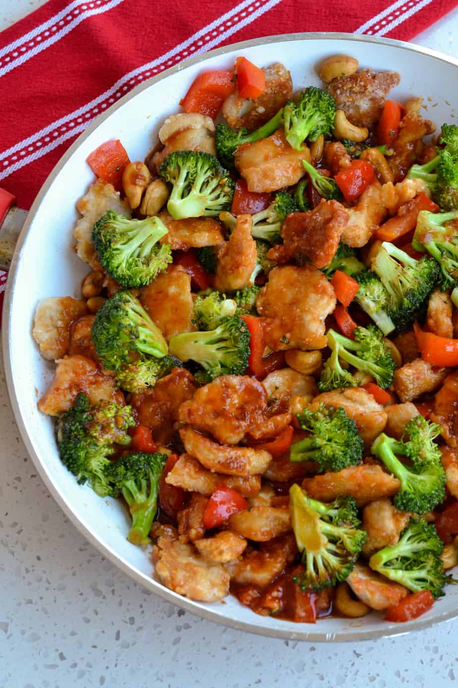 A skillet full of pan fried chicken, broccoli, red peppers and cashews in a sweet and spicy sauce. 
