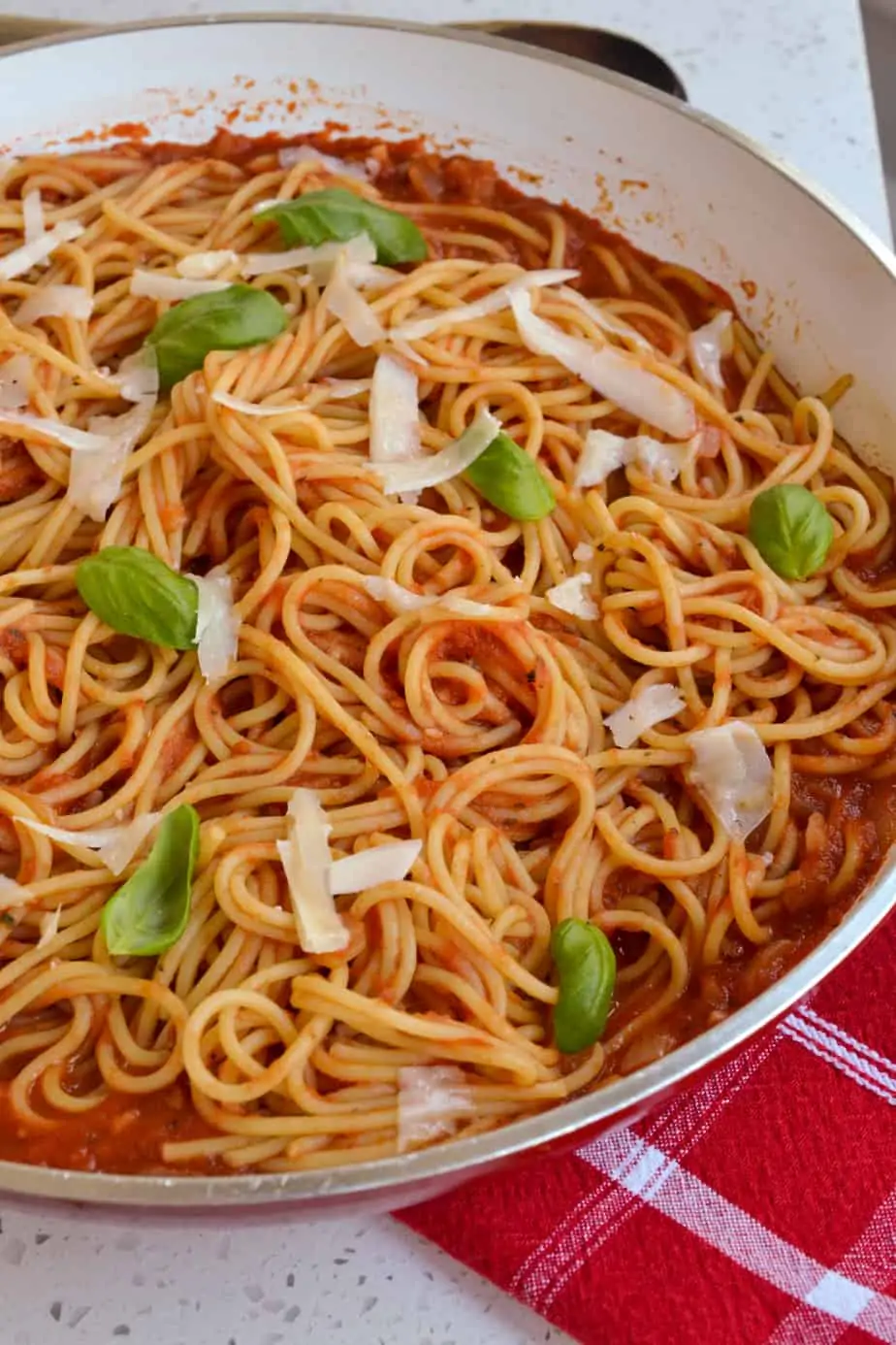 A skillet of spaghetti with tomato sauce. 