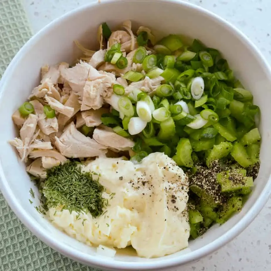 A bowl full of ingredients for a rotisserie chicken salad. 