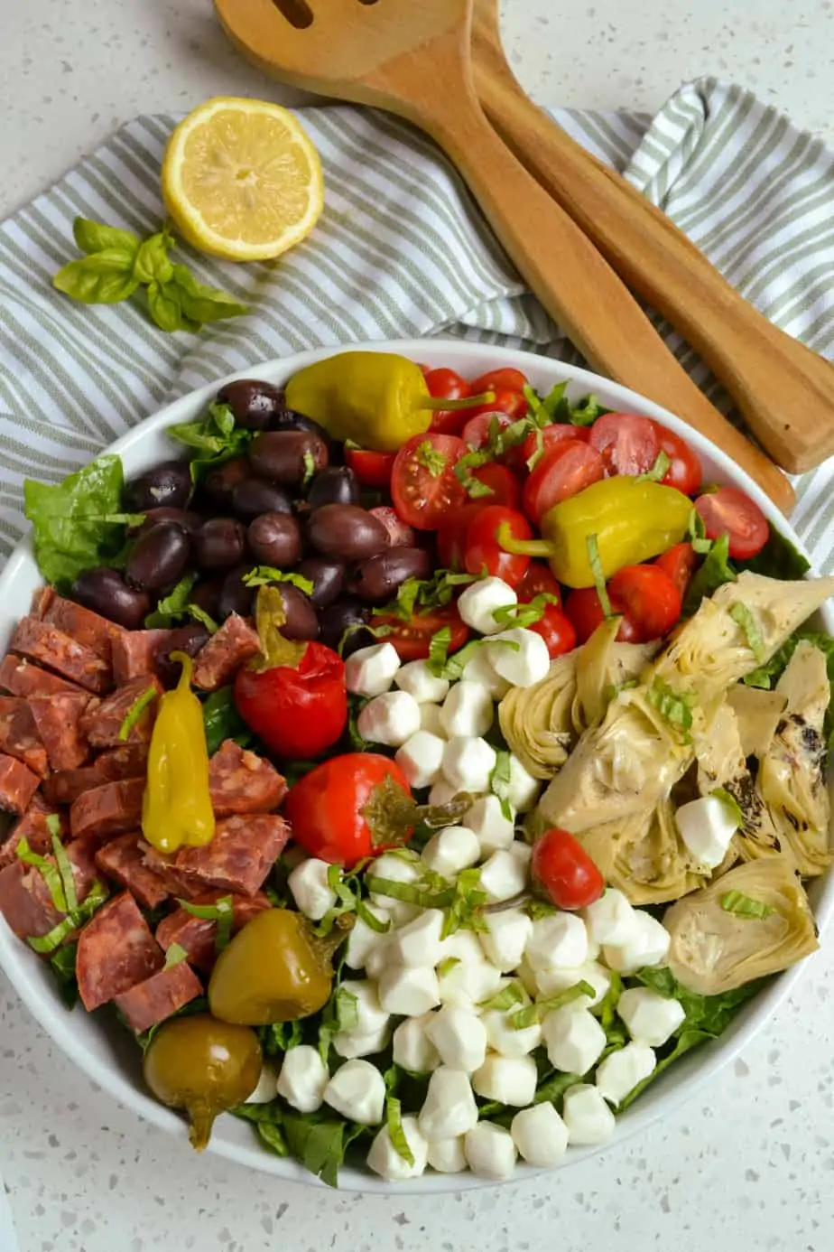 An overhead view of a bowl of antipasto salad with salami, mozzarella, tomatoes, and olives. 