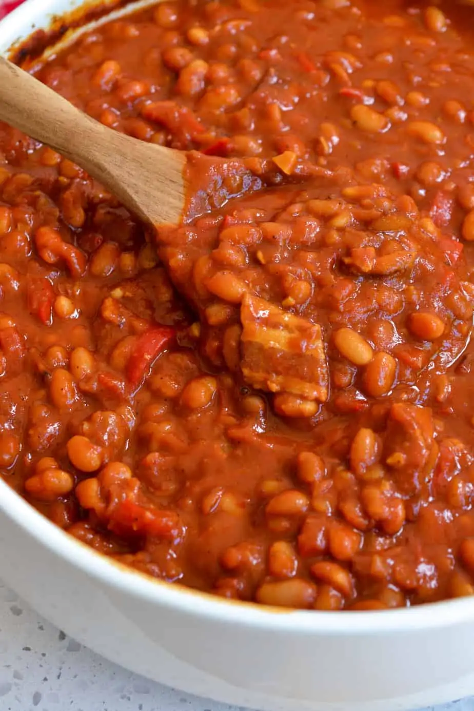 Company-worthy baked beans made with dried navy beans, smoked bacon, onions, garlic, and molasses in a sweet tangy sauce with just a touch of kick.  
