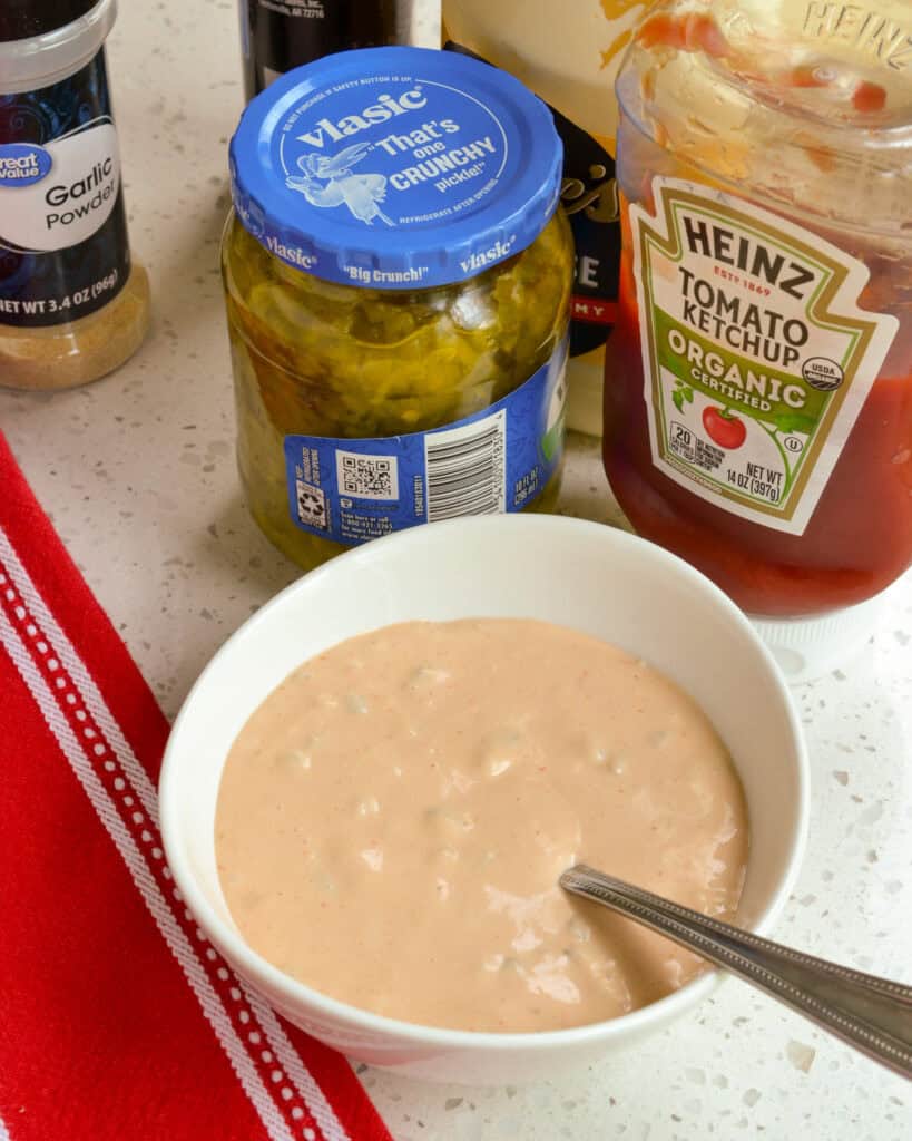 Burger sauce in a bowl in front of the ingredients to make it.