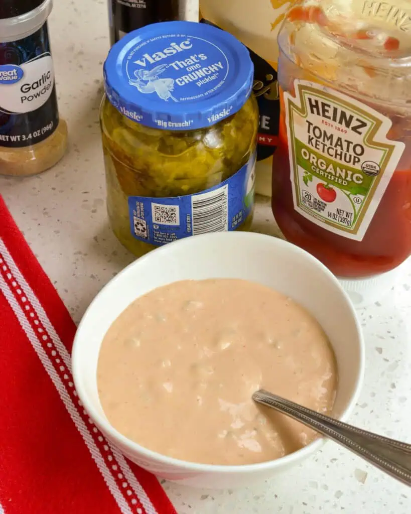 Burger sauce in a bowl in front of the ingredients to make it. 
