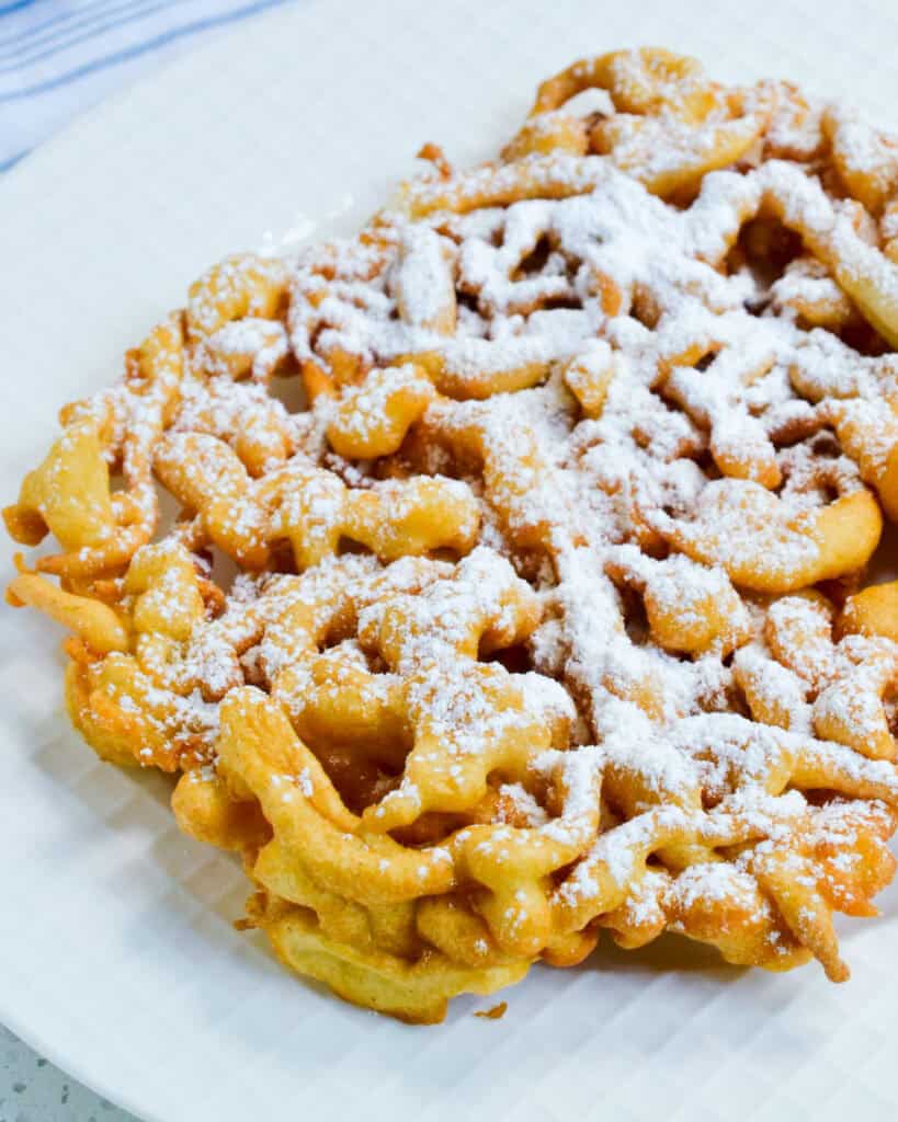 A close up view of funnel cakes sprinkled with powderd sugar. 