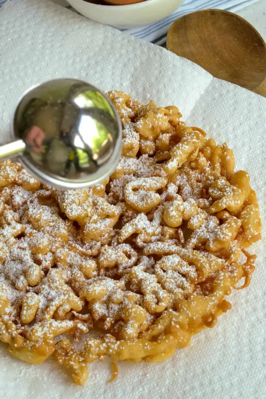 Dusting powdered sugar on funnel cake. 